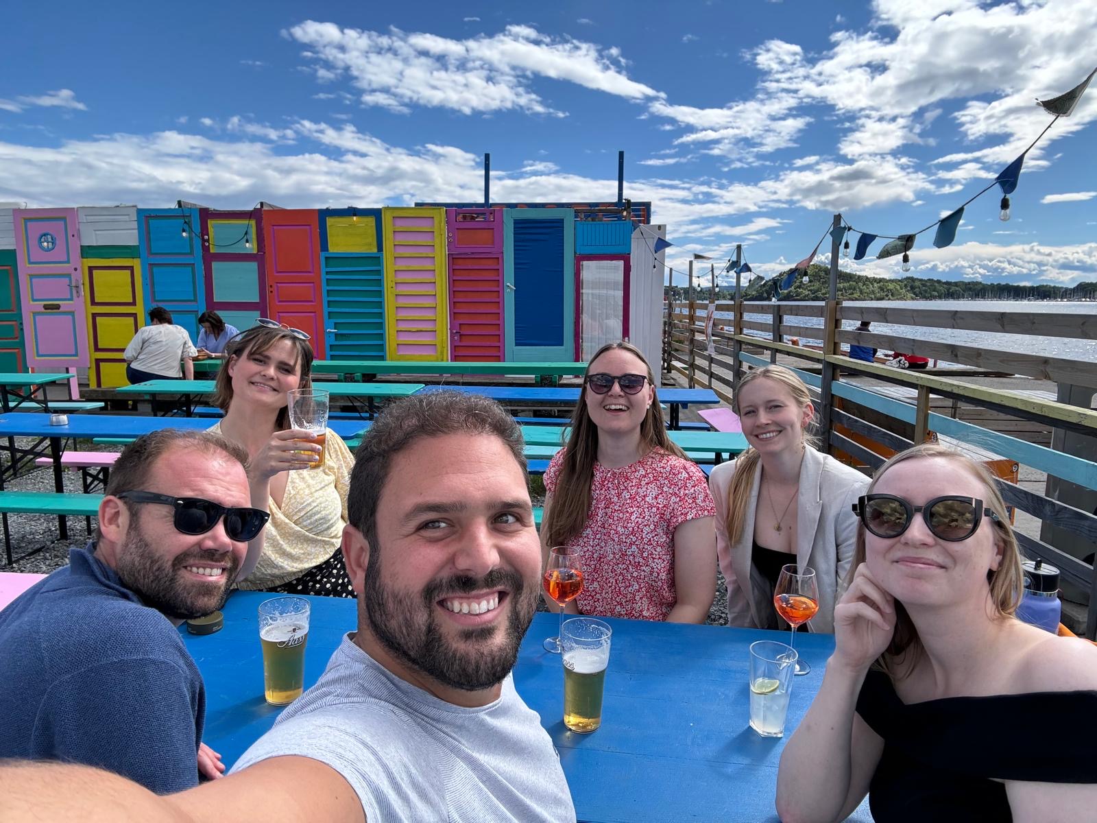 A group of people sitting at an outside table drinking beer.