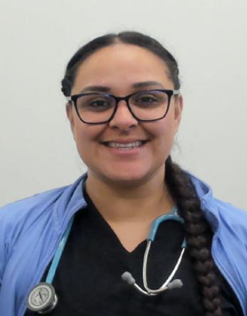 Smiling healthcare worker wearing glasses, braided hair, blue scrubs and stethoscope