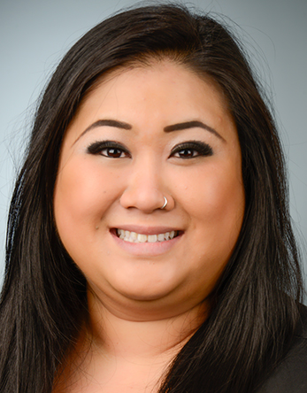 Studio headshot of smiling woman with long dark hair and a nose ring