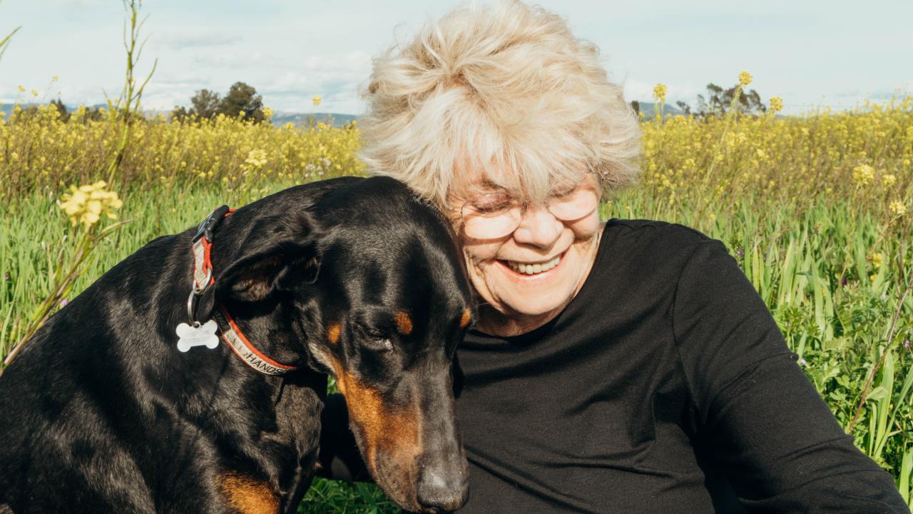 Handsome and his owner, Judith Friedman. Woman with dog, dog leaning in to her.