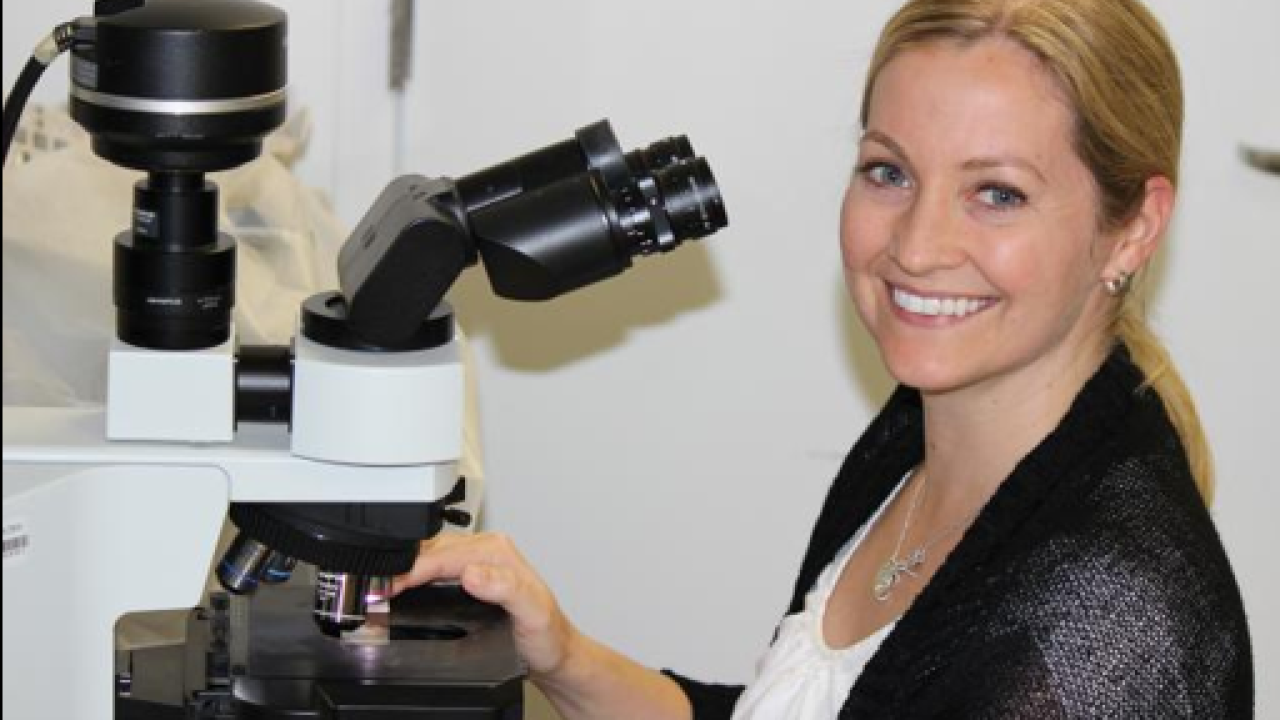 Patty Gaffney at microscope smiles at camera