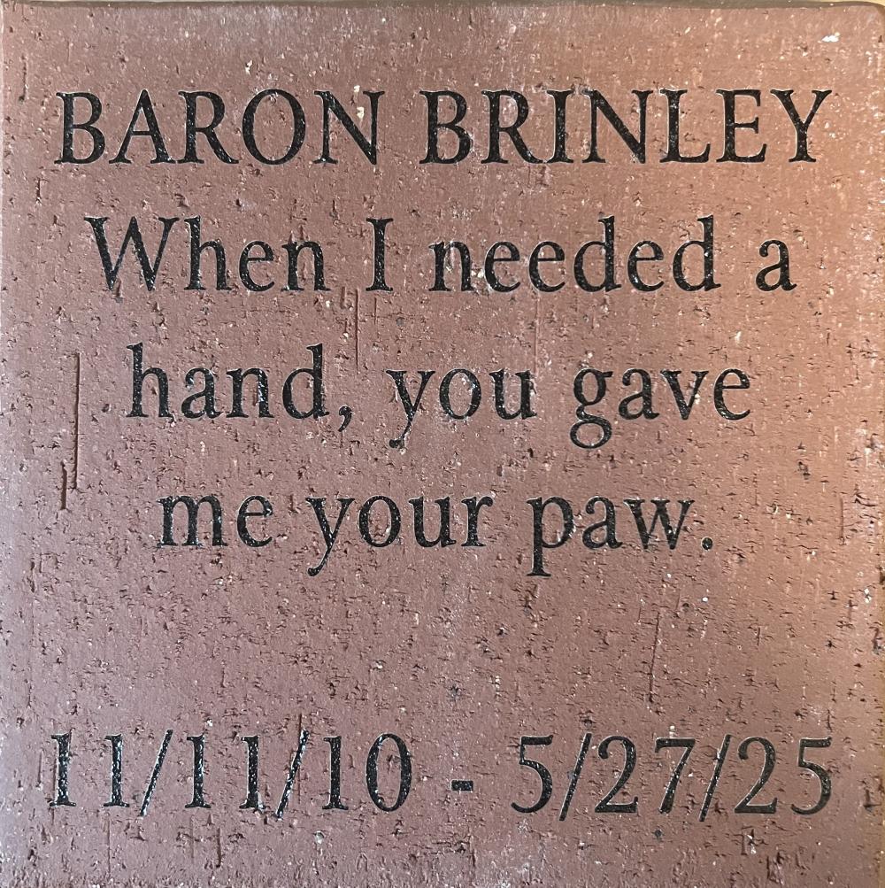 A red brick inscribed with BARON BRINLEY When I needed a hand, you gave me your paw. 11/11/10 - 5/27/25