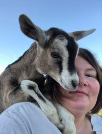 baby goat and woman with heads together