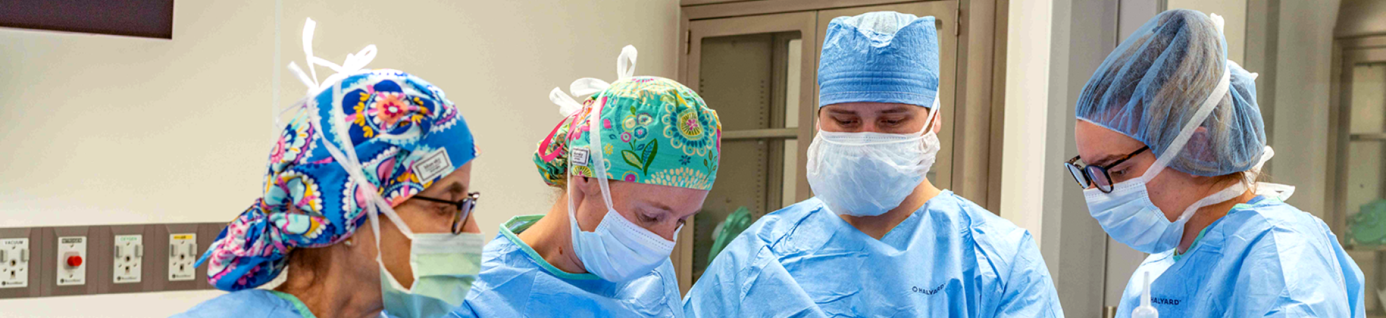 Four surgeons wearing scrubs while performing a procedure in the Advanced Veterinary Surgery Center.